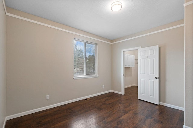 unfurnished bedroom with baseboards, dark wood finished floors, a spacious closet, and a closet