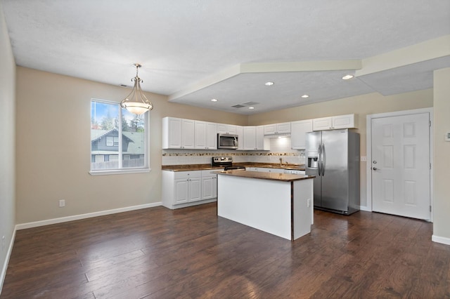 kitchen featuring appliances with stainless steel finishes, dark countertops, white cabinetry, baseboards, and decorative backsplash