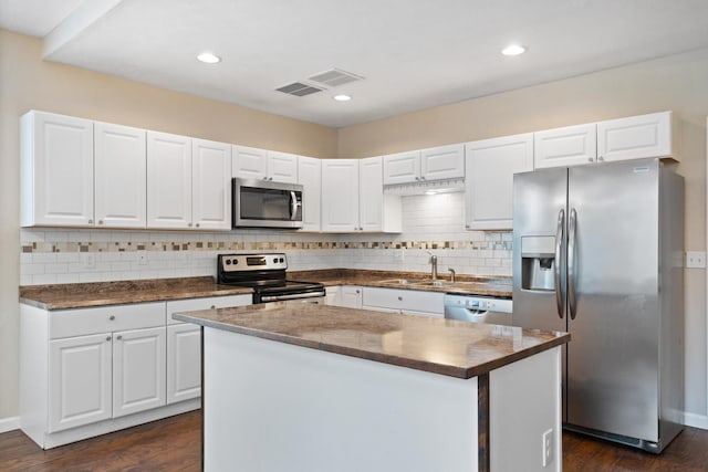 kitchen with stainless steel appliances, a sink, dark countertops, dark wood-style flooring, and recessed lighting