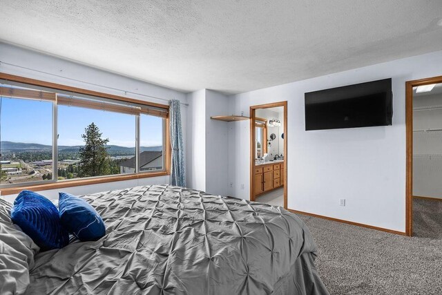 5612 N Vista Grande Dr, Otis Orchards, WA 99027 - bedroom with a textured ceiling, light carpet, baseboards, a walk in closet, and ensuite bath