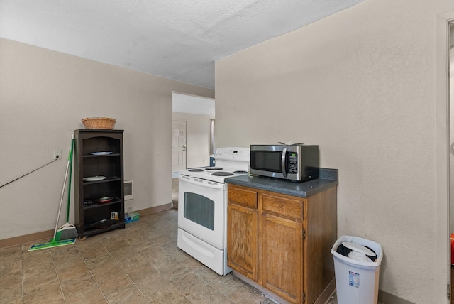 2124 N Dakota St, Spokane, WA 99207 - kitchen featuring electric stove, stainless steel microwave, dark countertops, baseboards, and brown cabinetry