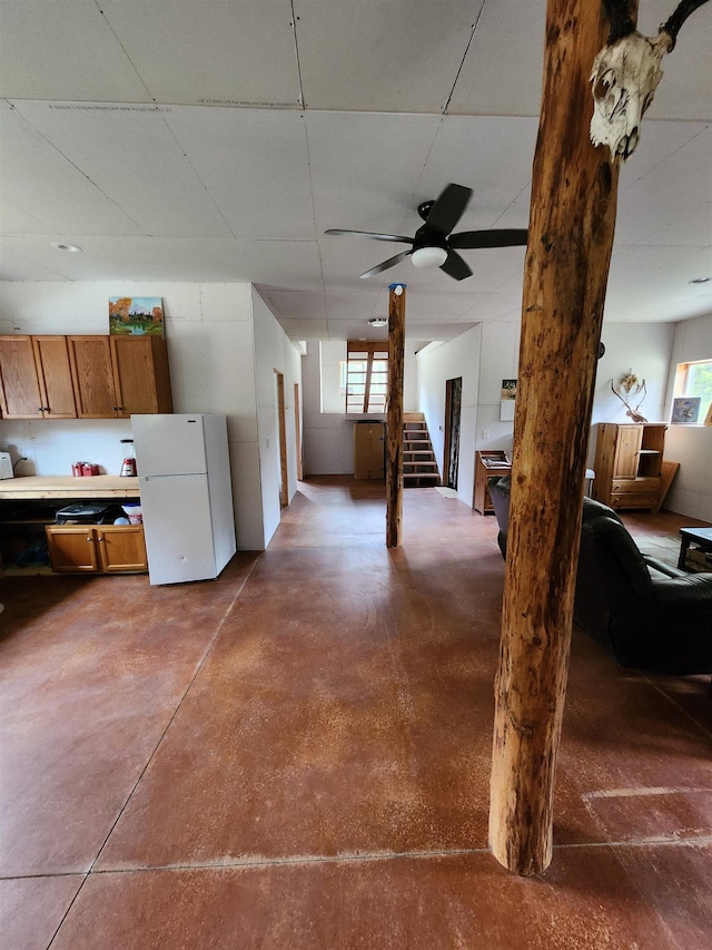 basement featuring freestanding refrigerator and stairway