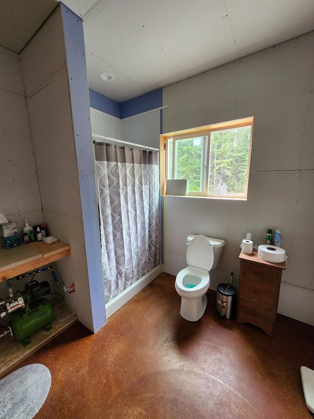 bathroom featuring toilet, concrete flooring, and a shower with shower curtain