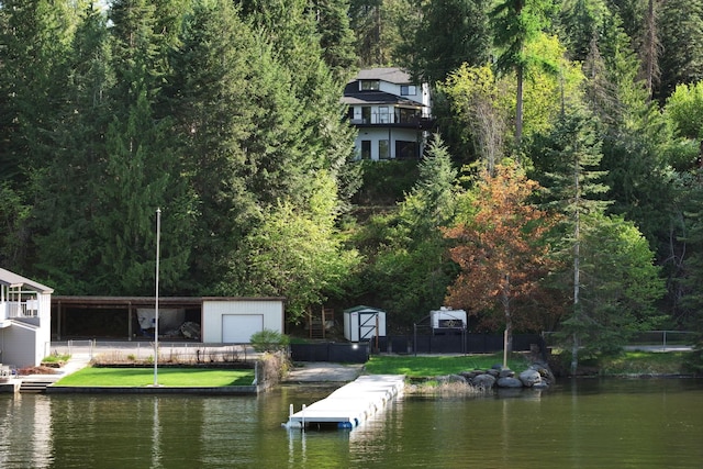dock with a water view, fence, and a wooded view
