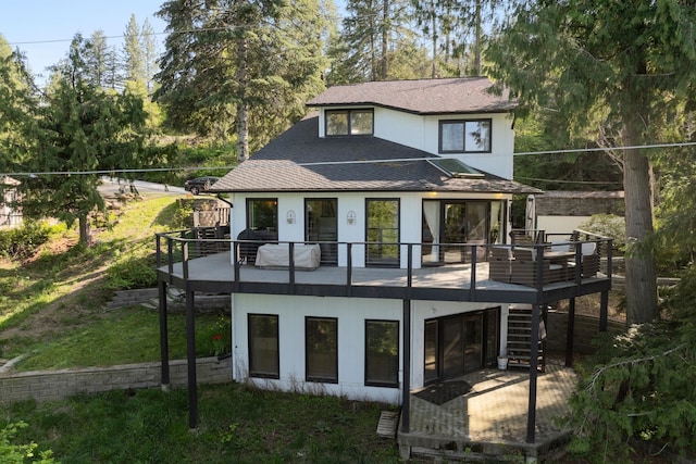 back of property with stairway, roof with shingles, and a deck