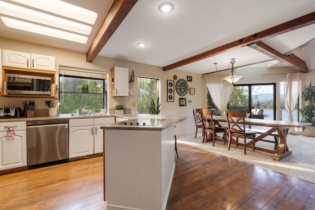 kitchen featuring stainless steel appliances, beam ceiling, white cabinetry, light wood-style floors, and recessed lighting