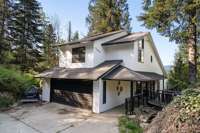 view of front of house with roof with shingles, a garage, a porch, and driveway