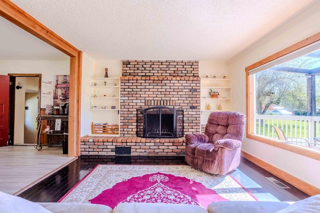211 4th St, Dover, ID 83825 - living room featuring a textured ceiling, wood finished floors, a fireplace, and baseboards