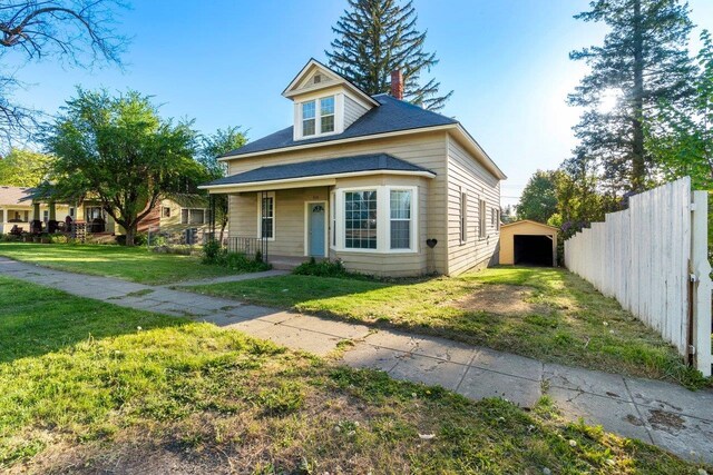 217 S Broadway St, Tekoa, WA 99033 - view of front facade with a porch, an outdoor structure, roof with shingles, and a chimney