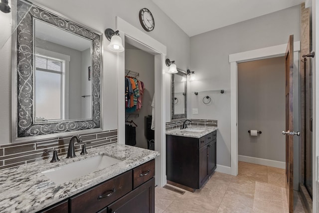 8504 E Black Oak Ln, Spokane, WA 99217 - full bathroom featuring two vanities, a walk in closet, backsplash, and baseboards