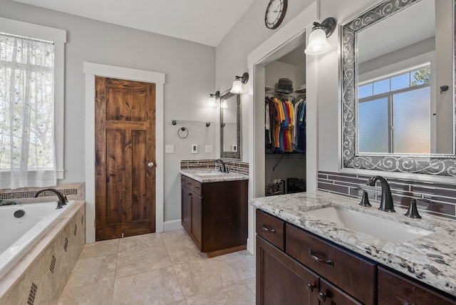8504 E Black Oak Ln, Spokane, WA 99217 - bathroom with two vanities, a relaxing tiled tub, backsplash, and tile patterned floors