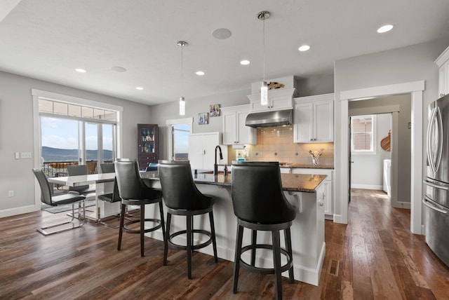 8504 E Black Oak Ln, Spokane, WA 99217 - kitchen featuring under cabinet range hood, dark wood-type flooring, freestanding refrigerator, backsplash, and white cabinets