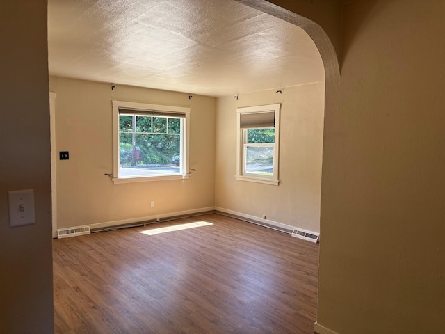 1711 E 14th Ave, Spokane, WA 99202 - unfurnished room featuring arched walkways, wood finished floors, baseboards, and a textured ceiling