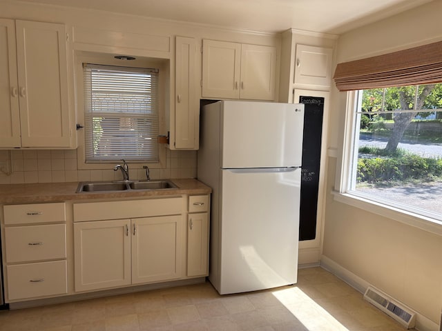 1711 E 14th Ave, Spokane, WA 99202 - kitchen with freestanding refrigerator, a sink, decorative backsplash, and white cabinetry