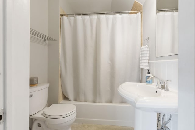 bathroom featuring toilet, shower / bath combo with shower curtain, and a sink