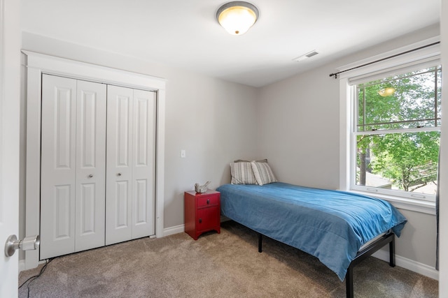 carpeted bedroom with a closet and baseboards