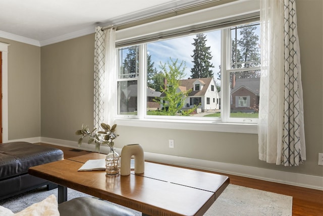 living area featuring crown molding, wood finished floors, and baseboards