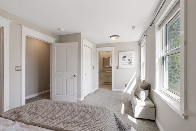 bedroom with carpet floors, baseboards, multiple windows, and ensuite bathroom