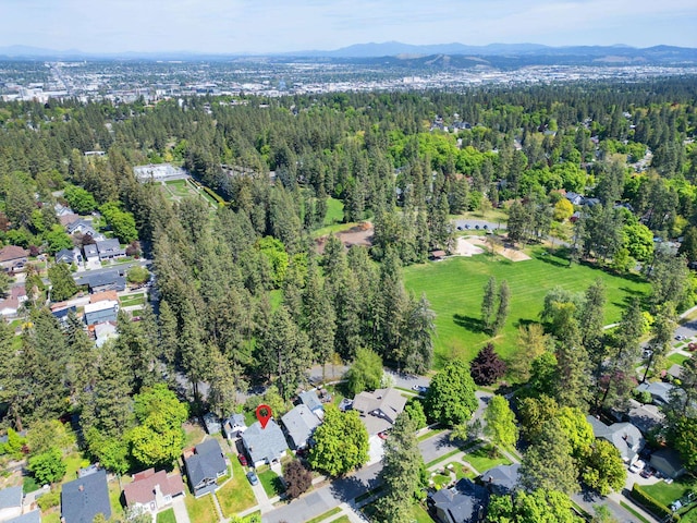 aerial view of property's location with a mountain backdrop and a heavily wooded area
