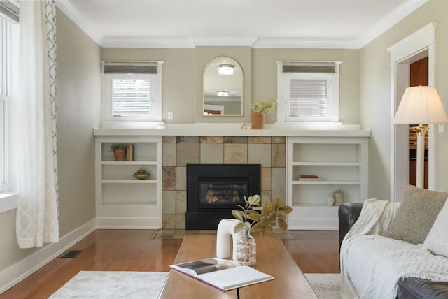 living room with wood finished floors, ornamental molding, a fireplace, and baseboards