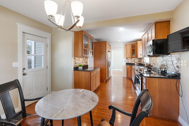 kitchen featuring stainless steel appliances, dark countertops, a chandelier, wood finished floors, and recessed lighting