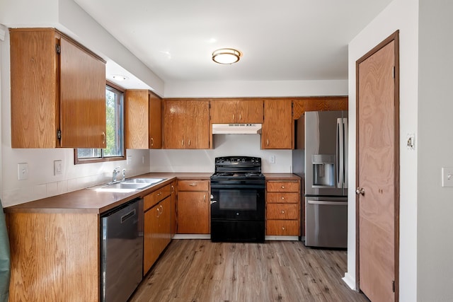 3326 E Pineglen Ave, Mead, WA 99021 - kitchen with appliances with stainless steel finishes, a sink, under cabinet range hood, light wood-type flooring, and brown cabinets