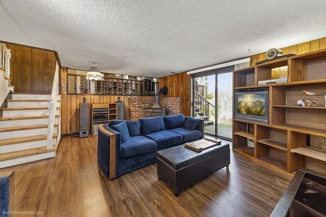 10511 E Cimmaron Dr, Spokane, WA 99206 - living room featuring wood walls, stairs, dark wood finished floors, a wood stove, and a textured ceiling