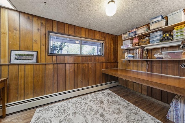 10511 E Cimmaron Dr, Spokane, WA 99206 - office with baseboard heating, wood walls, a textured ceiling, built in study area, and wood finished floors