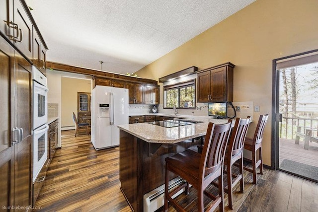 10511 E Cimmaron Dr, Spokane, WA 99206 - kitchen with white appliances, baseboard heating, dark brown cabinets, a sink, and dark wood-style flooring