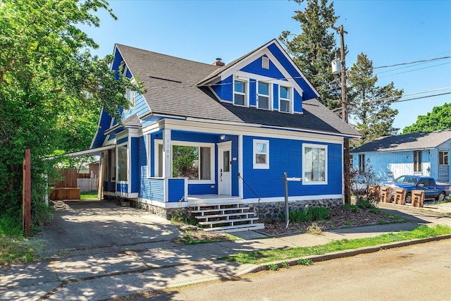 view of front of home featuring a porch, an attached carport, concrete driveway, fence, and roof with shingles