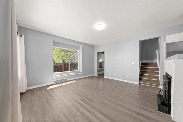 unfurnished living room featuring wood finished floors, baseboards, and a fireplace