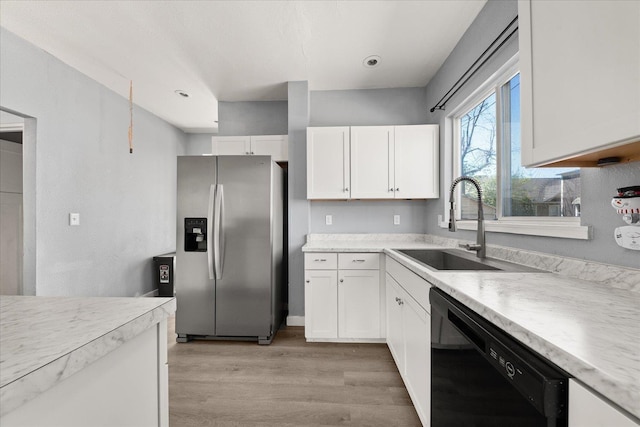 kitchen featuring stainless steel fridge with ice dispenser, black dishwasher, light wood-style floors, a sink, and white cabinetry
