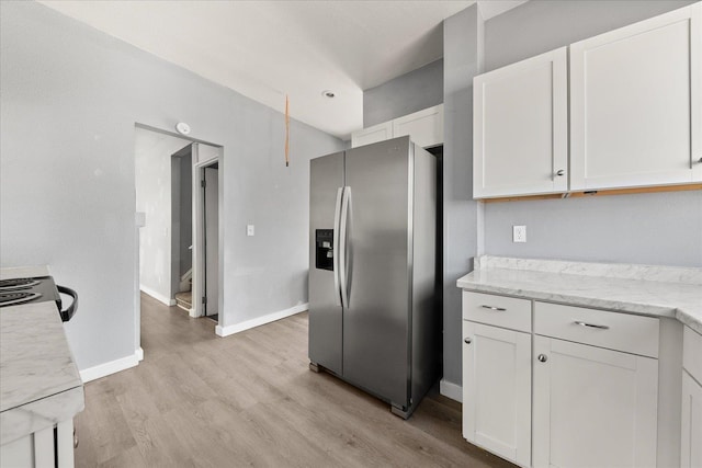 kitchen with stainless steel refrigerator with ice dispenser, white cabinetry, and light wood-style flooring
