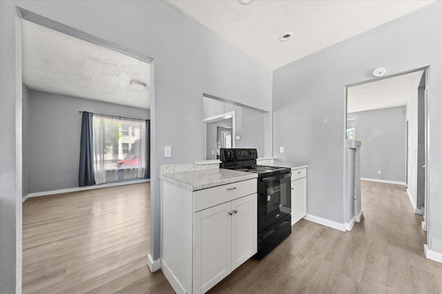 kitchen featuring black electric range, light wood-style floors, white cabinets, and light countertops