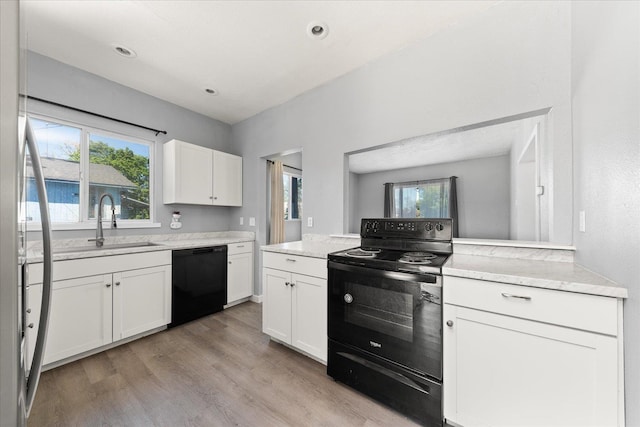 kitchen with black appliances, a sink, light wood-style floors, white cabinets, and plenty of natural light