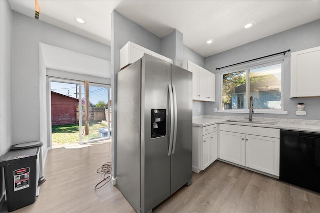 kitchen featuring stainless steel refrigerator with ice dispenser, black dishwasher, a sink, light wood-type flooring, and white cabinets