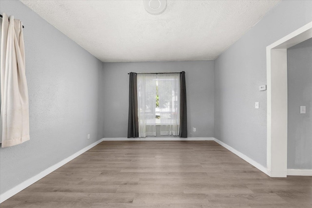 unfurnished room with wood finished floors, baseboards, and a textured ceiling