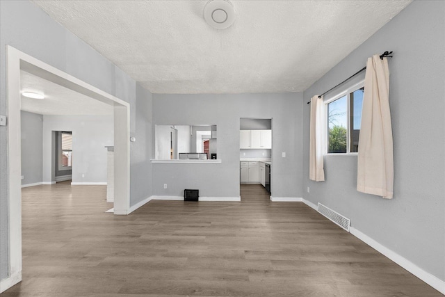 unfurnished living room with dark wood finished floors, a textured ceiling, and baseboards
