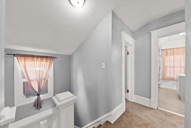 hall featuring lofted ceiling, carpet flooring, and baseboards