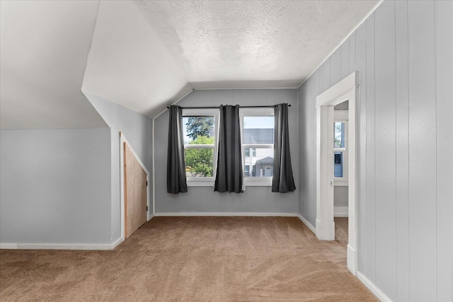 bonus room featuring carpet, vaulted ceiling, a textured ceiling, and baseboards
