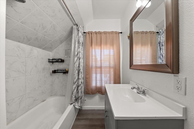 full bath featuring vaulted ceiling, vanity, wood finished floors, and shower / bath combo