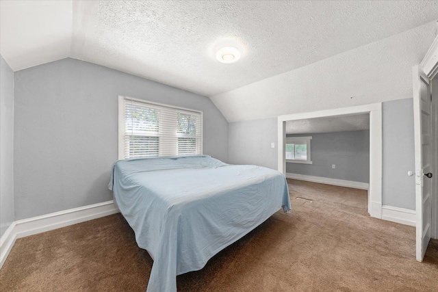 bedroom with lofted ceiling, baseboards, carpet flooring, and a textured ceiling