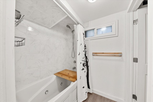 bathroom with shower / tub combo, wood finished floors, and baseboards