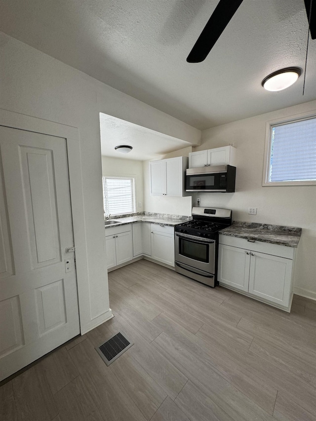 2209 N Washington St, Spokane, WA 99205 - kitchen featuring appliances with stainless steel finishes, white cabinetry, a sink, a textured ceiling, and a ceiling fan