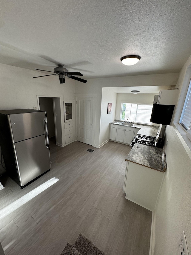 2209 N Washington St, Spokane, WA 99205 - kitchen with freestanding refrigerator, gas range, light wood finished floors, a sink, and ceiling fan