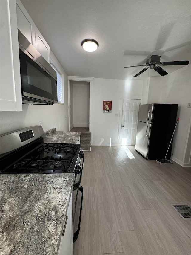 2209 N Washington St, Spokane, WA 99205 - kitchen featuring appliances with stainless steel finishes, light wood-style flooring, white cabinetry, and a ceiling fan