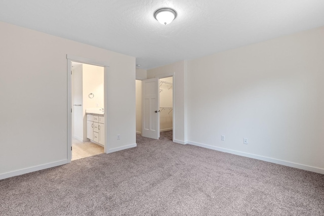 18420 E 1st Ln, Spokane Valley, WA 99016 - unfurnished bedroom with light carpet, a spacious closet, baseboards, a closet, and ensuite bath
