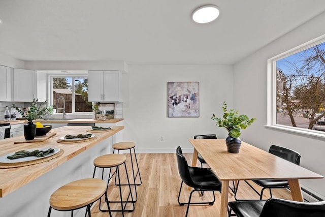 dining space featuring light wood finished floors and baseboards