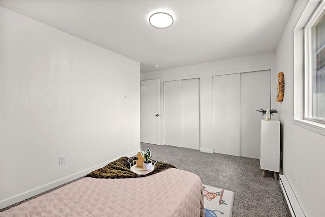 carpeted bedroom with two closets and a baseboard heating unit