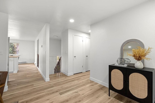 corridor with light wood-type flooring, baseboard heating, recessed lighting, and baseboards
